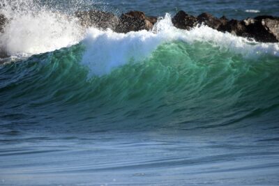 Blue-green wave near a rocky outcropping in Port Hueneme, California.