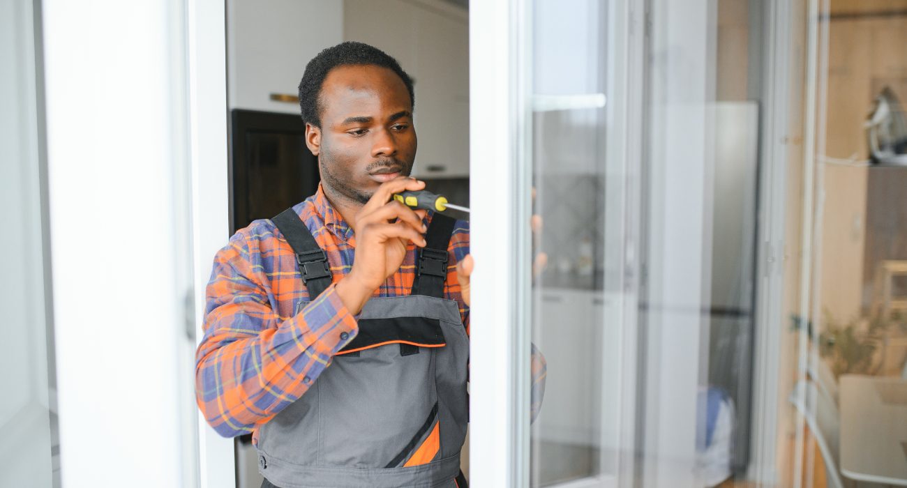 Geeks on Site technician repairing a Ring video doorbell next to a front door using a screwdriver.