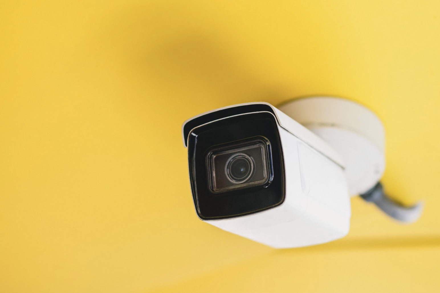 Wired security camera on yellow background
