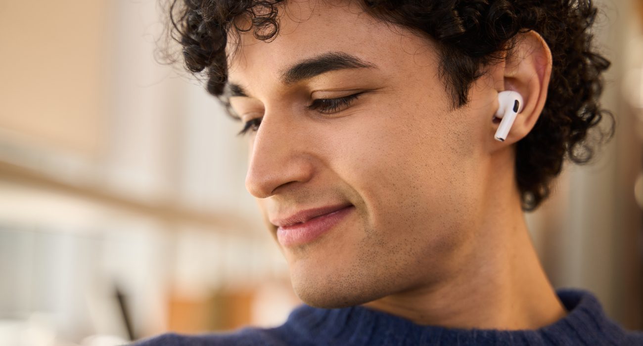 A young man using AirPods connected to a Dell laptop for wireless audio