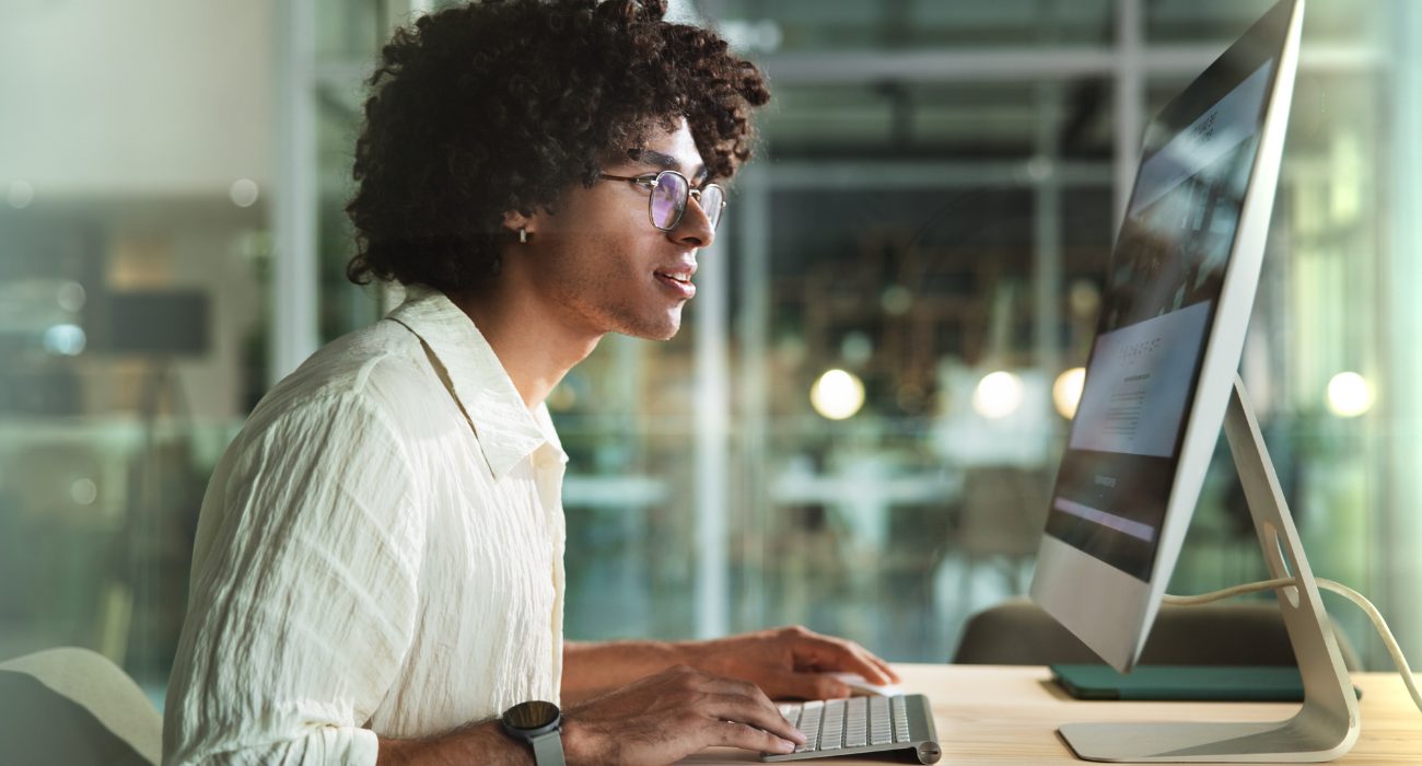 Young man working on a desktop computer with multiple applications open, illustrating how RAM affects multitasking performance
