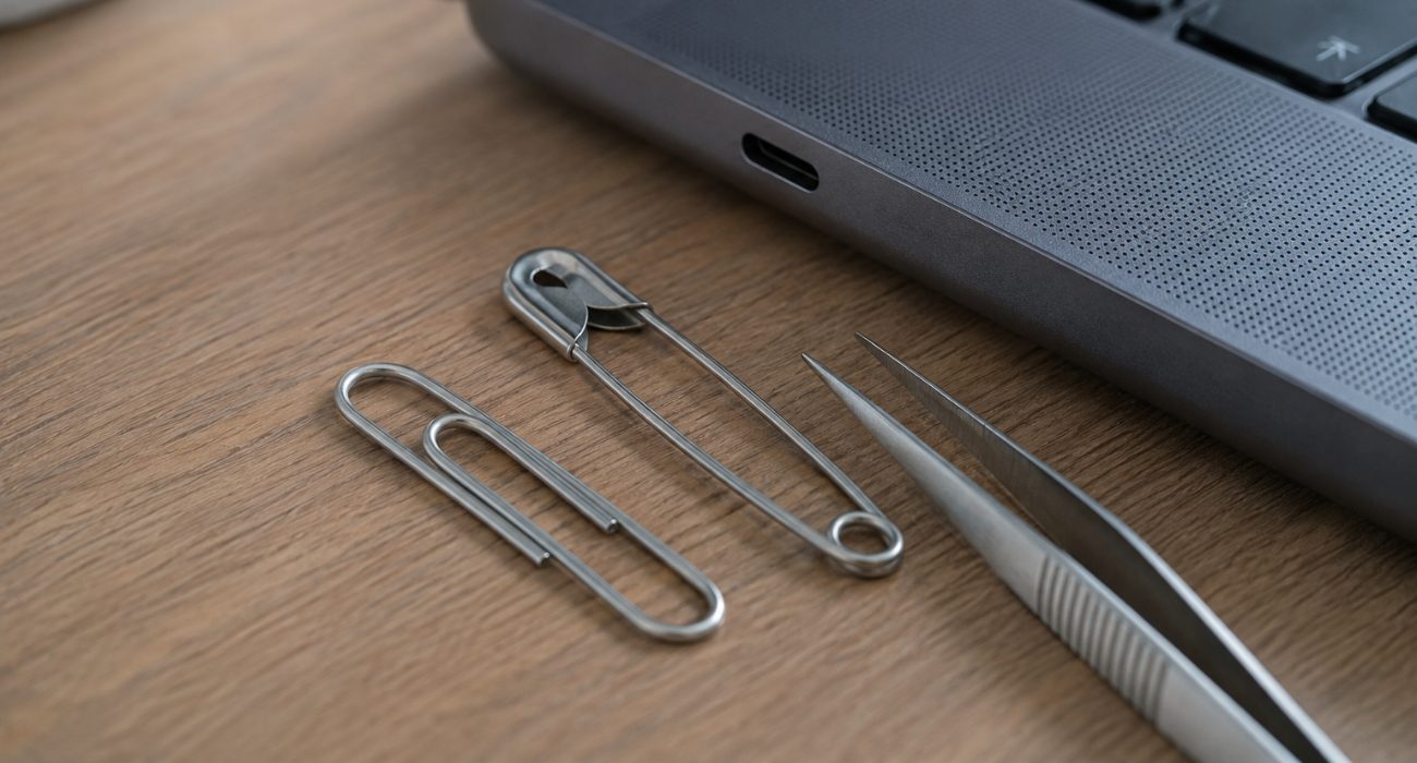 Metal tools to avoid when cleaning a USB port, including a paper clip, safety pin, and tweezers