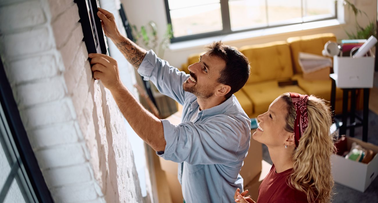 Couple positioning a TV wall mount at a comfortable viewing height